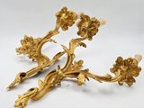 a pair of gold plated candlesticks with flowers and leaves