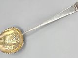 a silver spoon with a flower on it on a gray surface