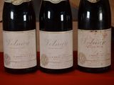 three bottles of wine are lined up on a red table