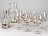 Plusieurs verres à vin et une carafe sont alignés sur une table