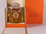 une boîte orange contenant un flacon de parfum, posée sur une surface blanche