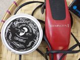 a red hair dryer sitting on a wicker tray next to a container of hair products