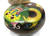 a black box with a dragon design on it next to a vase