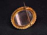 a gold plated brooch with a needle sticking out of it