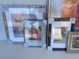 many framed pictures on a table with a banana in the background