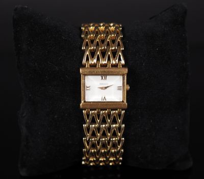 a gold watch with a white face on a black cushion