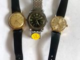 three watches are sitting next to each other on a white surface