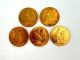 four gold coins sitting on top of each other on a white surface