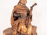 statue of a man sitting on a pile of books with a sword