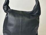 Le grand sac en cuir noir est posé sur une surface blanche.