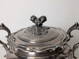 a silver teapot with a bird on top of it