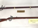 two guns are on display in a glass case on a white surface