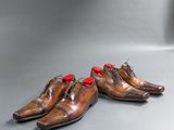 two pairs of brown shoes with red laces sitting on a gray surface