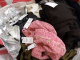 a pile of clothes in a suitcase with tags on it