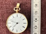 une petite montre de poche en or avec des chiffres romains