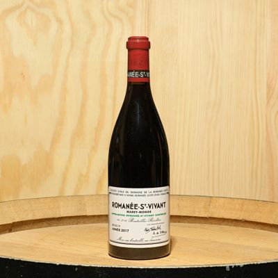 a bottle of wine sitting on top of a barrel