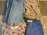 trois paires de jeans et un t-shirt posés sur un lit