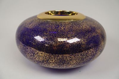un vase violet bordé d'or posé sur une table blanche