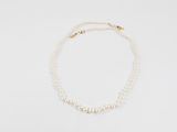 un collier de perles blanches avec un fermoir en or sur fond blanc