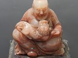 statue représentant un homme tenant un bébé dans ses bras, assis sur un rocher