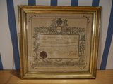 an old framed picture of a certificate on a wooden table