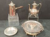 a silver tea pot and a silver plate on a table