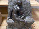 statue d'une femme assise sur un rocher dans une pièce
