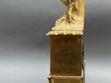 brass figurine of a woman sitting on a bench with a bird on it
