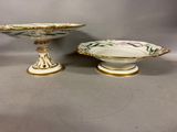 two white and gold dishes with flowers on them sitting on a table
