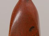 a brown vase sitting on a table with a white wall in the background