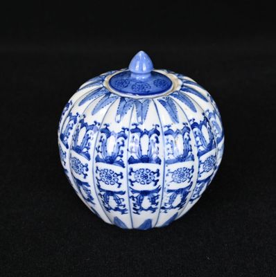 un vase bleu et blanc muni d'un couvercle, posé sur une surface noire