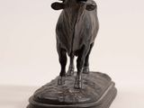 statue of a bull standing on top of a base on a white surface