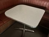 a corner booth with a table and a bench in the corner