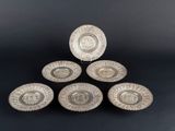 a set of four silver plated dishes on a black background