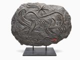 une image représentant une pierre ornée d'un motif, posée sur un socle