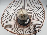 un panier en fil de fer contenant une lampe, posé sur une table