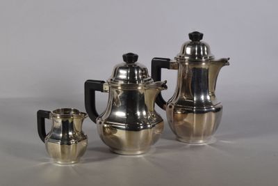 trois cafetières en argent et deux tasses en argent posées sur une table