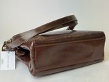 the brown leather bag is open and has a tag on it