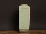 a green vase sitting on top of a wooden table