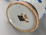 a close up of a blue and white vase with a bird on it