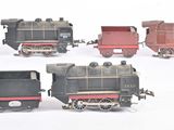 quatre petits trains miniatures alignés sur une surface blanche