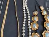 several different necklaces and bracelets on a table with a black background