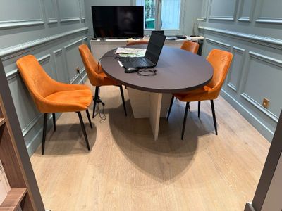a laptop on a table in a room with orange chairs