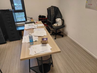 un bureau sur lequel sont posés des papiers et une chaise dans un coin