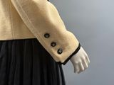une photo d'un mannequin portant une veste beige et une jupe noire