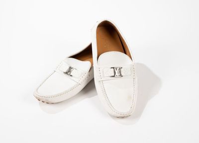 une paire de mocassins blancs ornés d'un monogramme sur le devant