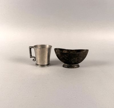 a silver cup and a silver cup on a white surface