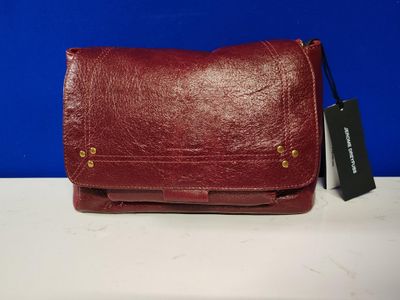 un sac à main en cuir rouge muni d'une étiquette, posé sur une table