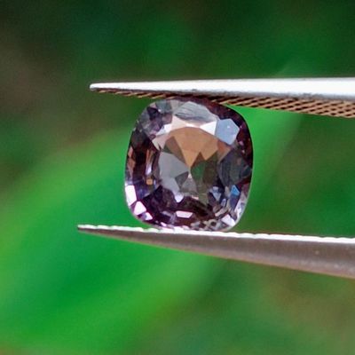 quelqu'un tient une pince dans laquelle est sertie un diamant violet