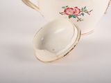 a tea pot with a spoon in it and a cup in front of it